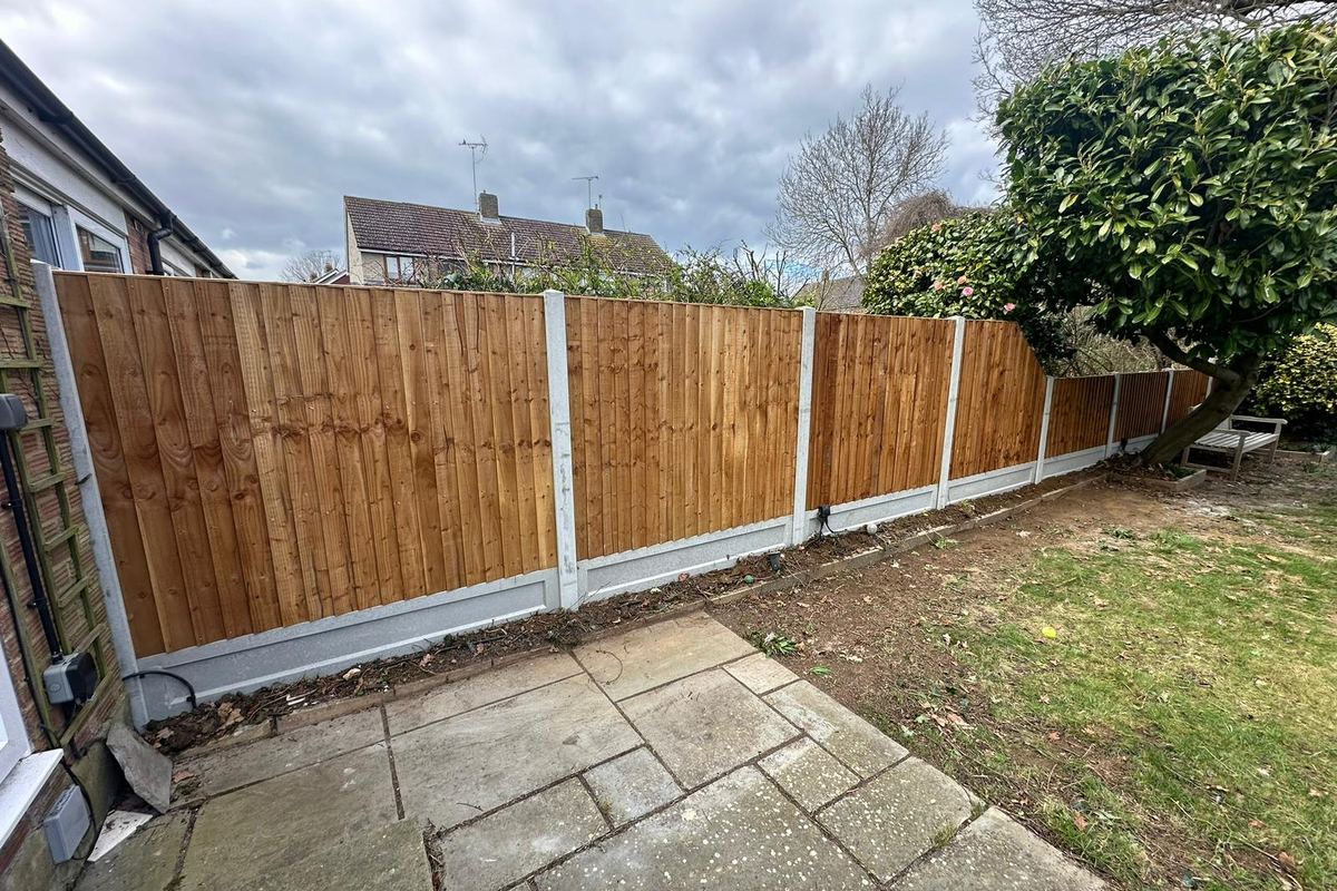 The same boundary after work: new closeboard fencing on concrete posts and gravel boards