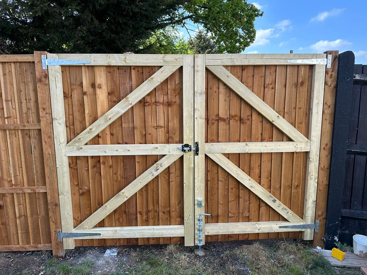 A pair of braced timber driveway gates on galvanised strap hinges