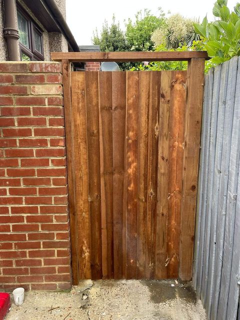 Timber gate fitted between a brick wall and an existing fence