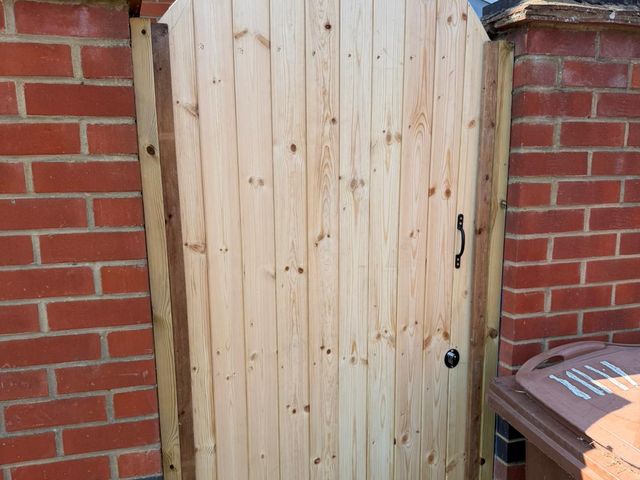 A new arched-top timber side gate hung between red brick piers
