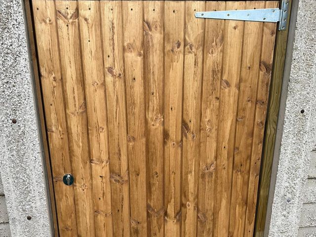 A closeboard door with galvanised strap hinges fitted into a concrete garage opening